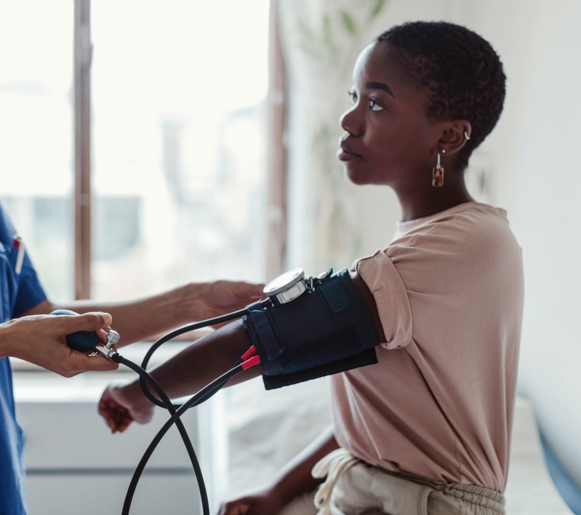 Nurse examining blood pressure of young female patient in medical examination room